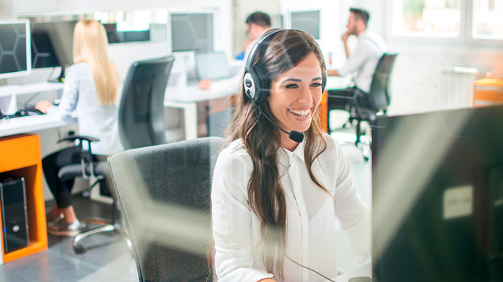 Lächelnde Person mit Headset am Arbeitsplatz